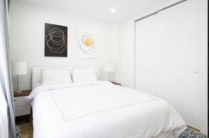a white bedroom with a white bed and a mirror at Beautifully Designed 3 BR Apartment in New York