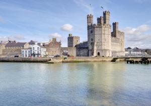 un castillo sentado sobre un cuerpo de agua en Ty Nain en Caernarfon
