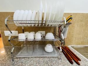 a dish rack filled with white plates and utensils at ALanKrita Homes in Lucknow