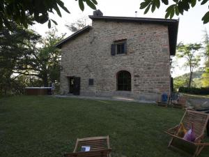 a stone house with two chairs in a yard at NatureMugello Oasi Naturista in Dicomano