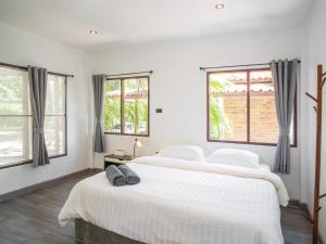 a white bedroom with a large bed and two windows at Sand Beach Bungalow in Klong Muang Beach