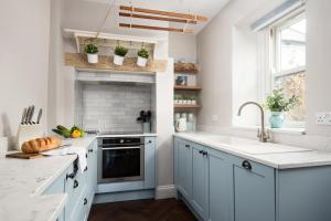 a kitchen with white cabinets and a sink and a window at Owl Cottage in Morpeth