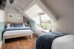 a attic bedroom with two beds and a window at Owl Cottage in Morpeth