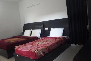 Cette chambre comprend 2 lits avec des draps rouges et des oreillers blancs. dans l'établissement Hotel Rajmahal, Rudrapur, à Rudrapur
