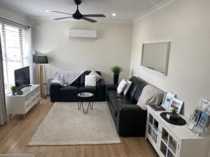 a living room with a black couch and a tv at Annie's Apartment in Mount Gambier