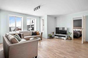a living room with a couch and a television and a bed at Warm and lovely apartment with free parking in Tromsø