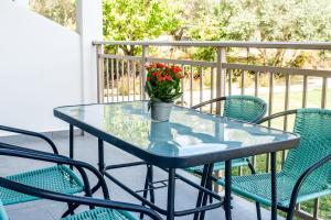 une table en verre avec un vase de fleurs sur le balcon dans l'établissement Ktima Holiday House, à Skiathos Chora