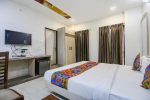 Dormitorio con cama, escritorio y TV en FabHotel Smriti Star, en Bhopal