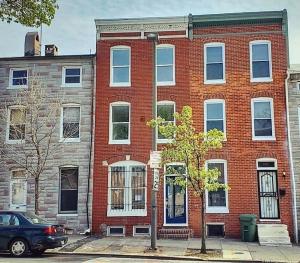 um edifício de tijolos vermelhos com um carro estacionado em frente em Budget Bed Room near Downtown Inner Harbor w Free Parking em Baltimore