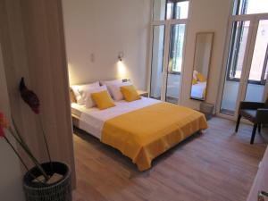 a bedroom with a large bed with yellow sheets and pillows at Kerameion in Athens