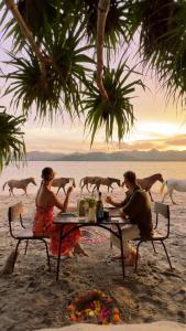 um grupo de pessoas sentadas numa mesa na praia em Gili Asahan Eco Lodge & Restaurant em Gili Asahan