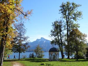 eine kleine Kapelle in einem Park neben einem Wasserkörper in der Unterkunft Ferienwohnung Alpenseepark in Mondsee