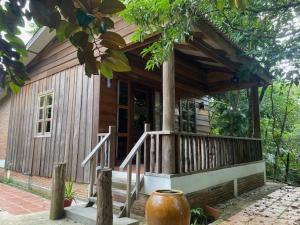 una pequeña casa de madera con porche y árbol en Kraoul Seh - Horse Riding Cambodia, en Kampot