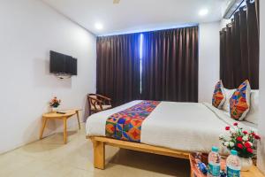 a bedroom with a bed and a window with a television at FabHotel The Green Leaf in Kondapur