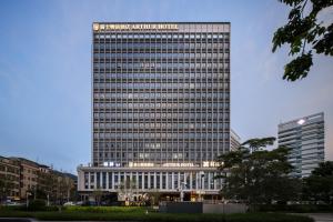 広州市にあるArthur Hotel Luogang Xiangang Metro Guangzhou-Free Breakfast and Free Afternoon Teaの正面に看板がある高い建物