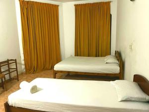 two beds in a room with orange curtains at Mimosha Holiday Inn in Rambukkana
