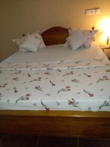 a bed with a white comforter with flowers on it at Mimosha Holiday Inn in Rambukkana