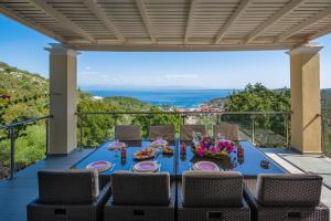 una mesa y sillas en un patio con vistas al océano en Red Rose Artistsvillas, en Gáios