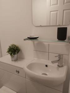 a white bathroom with a sink and a mirror at The Cozy Landport Loft in Portsmouth