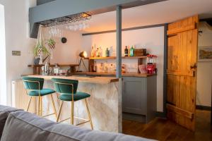 een keuken met een bar met twee groene barkrukken bij The Waterfall Retreat in Penrith