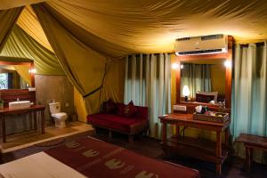 um quarto com uma tenda com uma cadeira vermelha em River Glamping by Gaga bees em Udawalawe