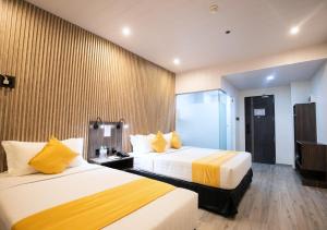 Habitación de hotel con 2 camas con sábanas amarillas en City Pod Hotel, en Cebú