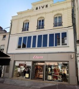 - un bâtiment blanc avec des fenêtres bleues dans une rue dans l'établissement 10 rue Carnot, à Montceau-les-Mines