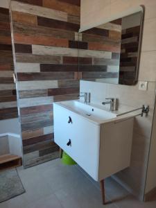 a bathroom with a white sink and a wooden wall at Les Terrasses du Phenix in Saint Alban Auriolles +18 photos