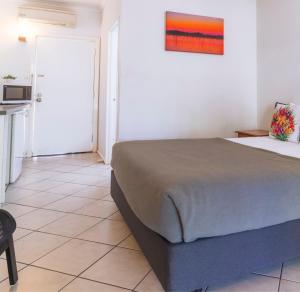 a bedroom with a large bed and a kitchen at Kimberley Croc Motel in Kununurra