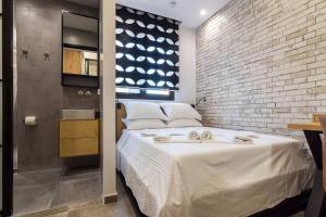 - une chambre avec un grand lit et un mur en briques dans l'établissement Emilie in Athens - Central design awarded flat Syntagma E3, à Athènes