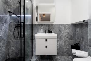 a bathroom with a white sink and a shower at Malila Premium Apartments Cracow Centre Grzegórzecka 15 in Krakow