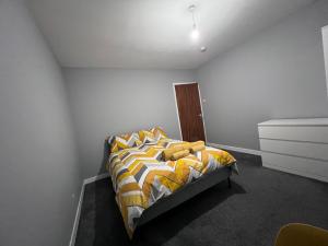 a bedroom with a bed with a yellow and white comforter at Modern Room Close to Warwick University in Canley
