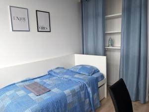 um quarto com uma cama com um edredão azul em Belle chambre lumineuse dans appartement em Évry-les-Châteaux