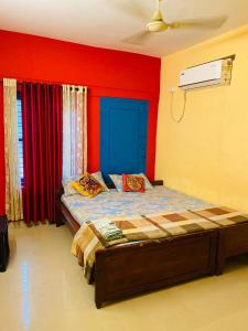 a bedroom with a bed with a blue headboard and red walls at Varkala Vibe in Varkala