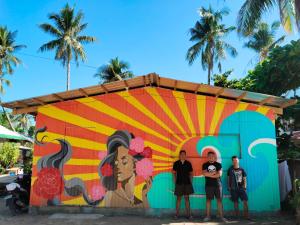 un grupo de tres hombres parados frente a un mural en Alegreya Homestay + Cafe en General Luna