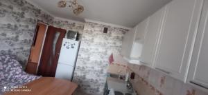 eine Küche mit weißen Schränken und einem weißen Kühlschrank in der Unterkunft Кенесары Жубанова in Astana