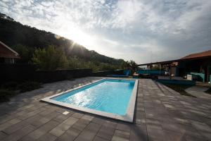 a swimming pool on a patio with the sun in the background at BlackMintHouse in Rakovac