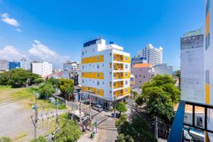a tall white building with yellow windows in a city at Gold Holiday Hotel in Vung Tau