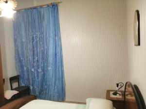 1 dormitorio con cortina azul y ventana en Appartamento con una camera matrimoniale, bagno in camera cucina e veranda esterni, en Rilievo