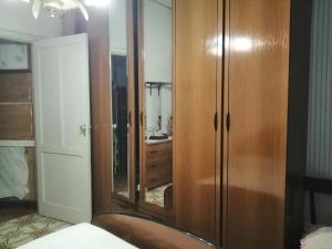 1 dormitorio con armario de madera y espejo en Appartamento con una camera matrimoniale, bagno in camera cucina e veranda esterni, en Rilievo