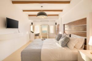 a bedroom with a large bed and a television at Apeiron Blue Santorini - Sustainable Adult-Only Retreat in Fira