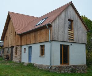 un granero con techo de metal y una casa blanca en Ferienwohnung Uckermarkblick, en Ziehten