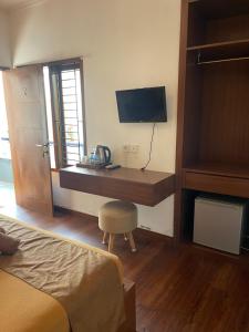 a bedroom with a desk with a television and a bed at The Kayuri in Canggu