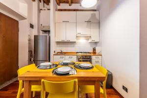 a kitchen with a wooden table and yellow chairs at Duomo-Porta Romana "Casa del Pittore" in Milan