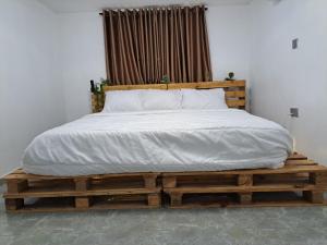 un letto in legno con lenzuola e cuscini bianchi di Igbalode Luxury Apartment a Ibadan