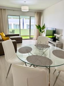 a living room with a glass table and white chairs at Lido Casa by Olá Madeira in Funchal