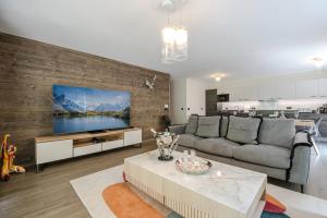 een woonkamer met een bank en een tv aan de muur bij WHITE PEARL in Chamonix-Mont-Blanc