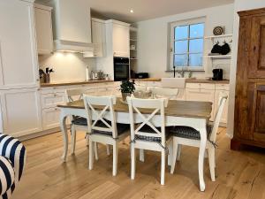 a white kitchen with a wooden table and chairs at Villa Rosenhof (4 Personen +) in Lindau