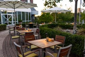 un patio al aire libre con mesas, sillas y sombrillas en Heidelberg Marriott Hotel en Heidelberg