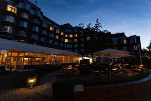 ein Hotel mit Tischen und Sonnenschirmen vor einem Gebäude in der Unterkunft Heidelberg Marriott Hotel in Heidelberg